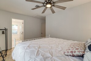 Une chambre à coucher avec un lit, un ventilateur de plafond et une porte donnant sur un balcon.
