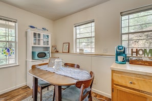 A dining area with a wooden table, chairs, a cabinet with glass doors, a microwave, and a coffee maker. - Family-friendly 'forest Cabin' w/ Hot Tub (Applegate)