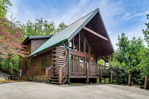 Eine Blockhütte mit Veranda, einer Treppe und einer Steinmauer.