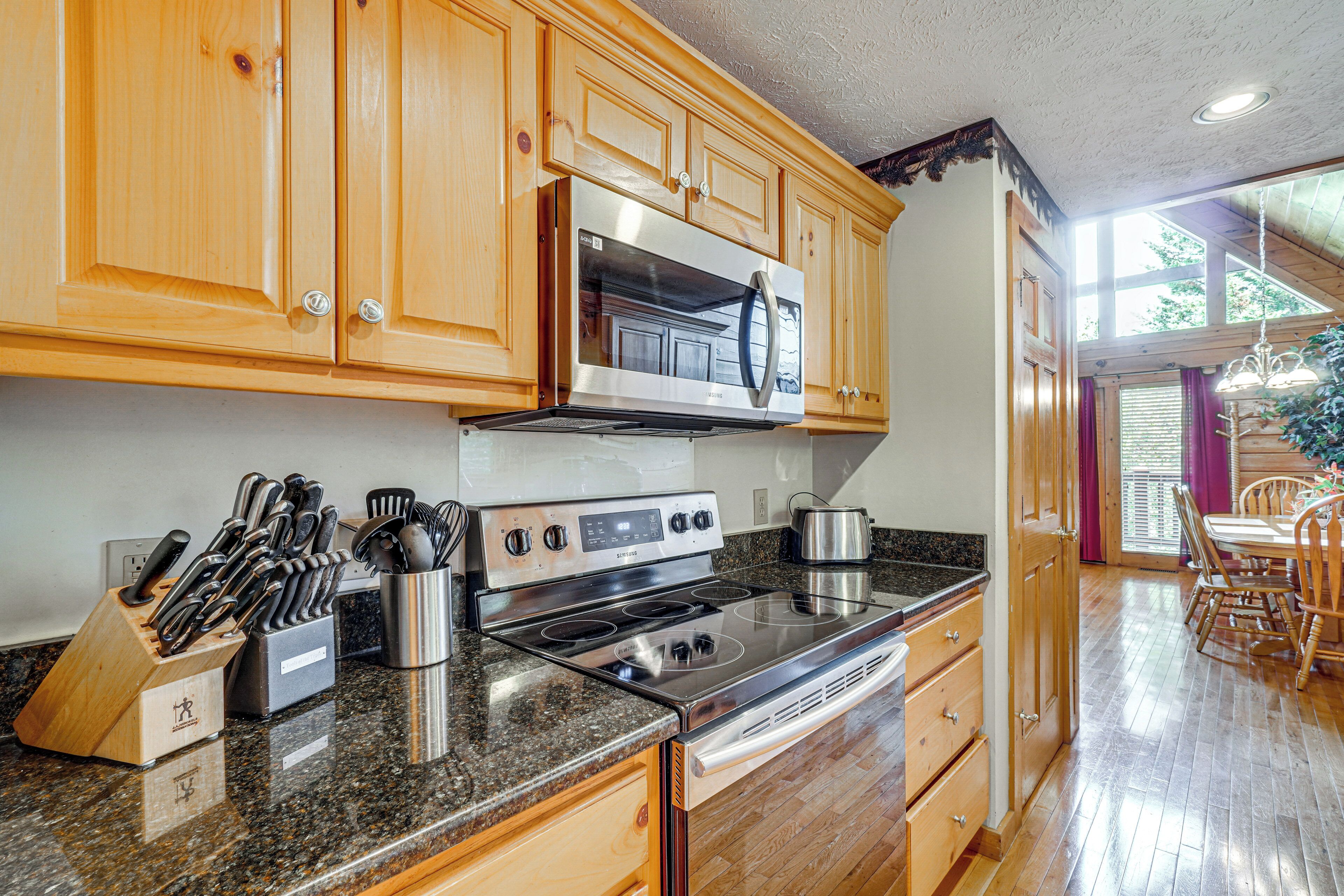 A kitchen with wooden cabinets, stainless steel appliances, granite countertops, and a dining area with wooden chairs.