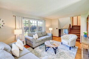 Una sala de estar con sofá, sillón, mesa de centro y una escalera.