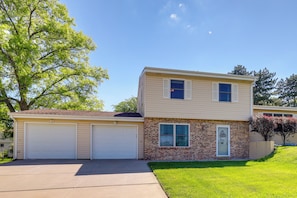 A two-story house with a garage, brick facade, and a well-maintained lawn. - Great for Families! Omaha Getaway w/ Yard & Deck (Omaha)