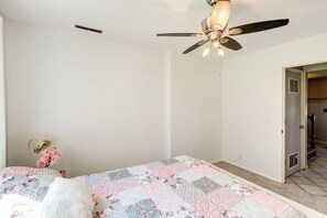 A bedroom with a bed, a ceiling fan, a nightstand, and a door leading to another room. - Great for Families! Omaha Getaway w/ Yard & Deck (Omaha)
