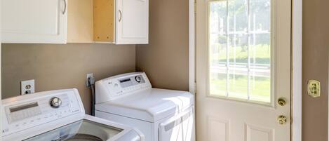 A laundry room with two front-loading washers and dryers, a cabinet above the dryers, and a door with a window.