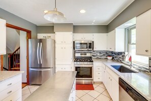 A modern kitchen with stainless steel appliances, white cabinetry, and a tiled backsplash. - Great for Families! Omaha Getaway w/ Yard & Deck (Omaha)