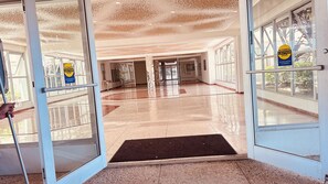 Eine Hotelhalle mit automatischen Schiebetüren, einem Marmorboden und Blick durch die Glastüren.