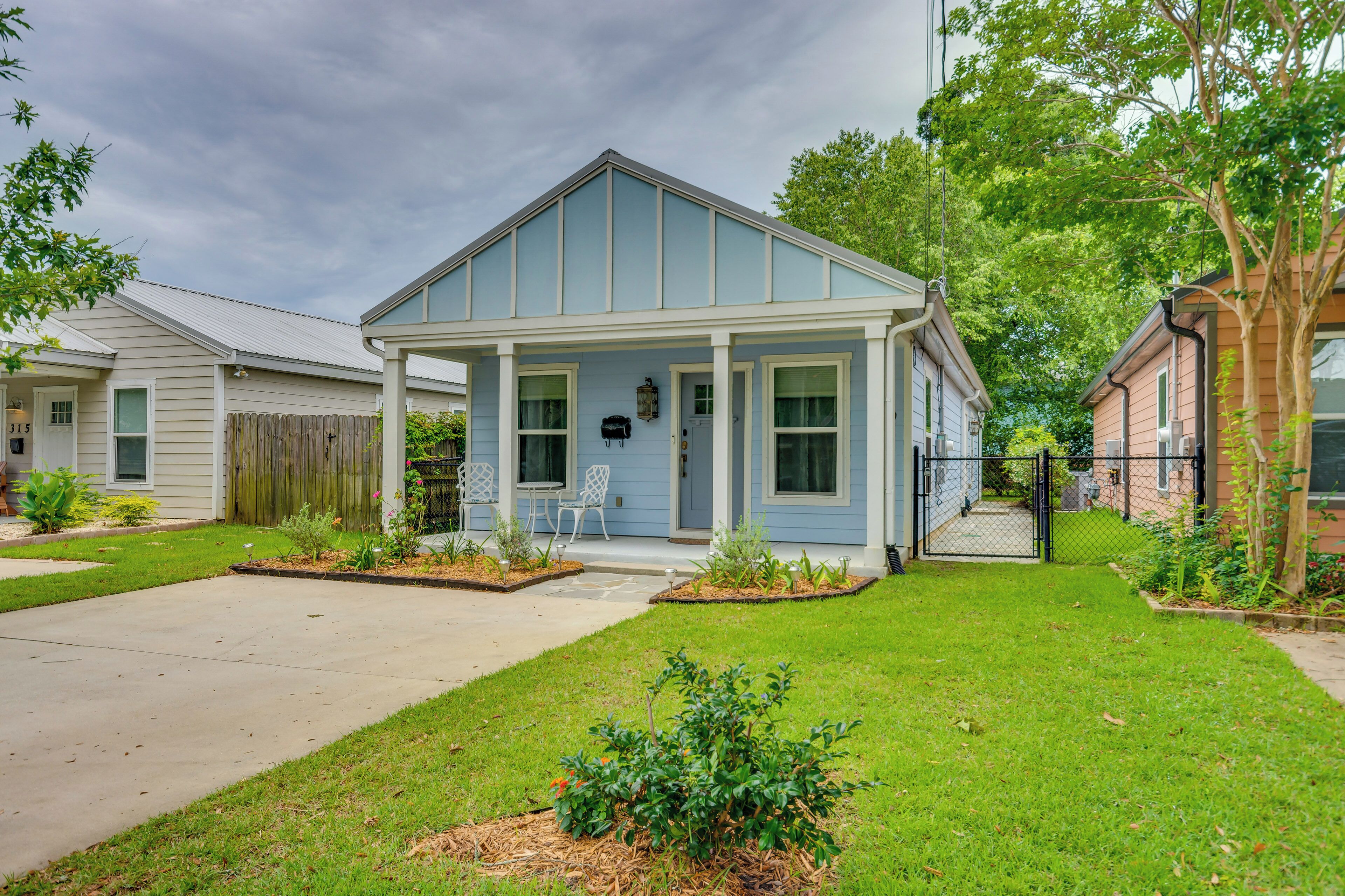 A single-story house with a front porch, a small garden, and a clear sky.