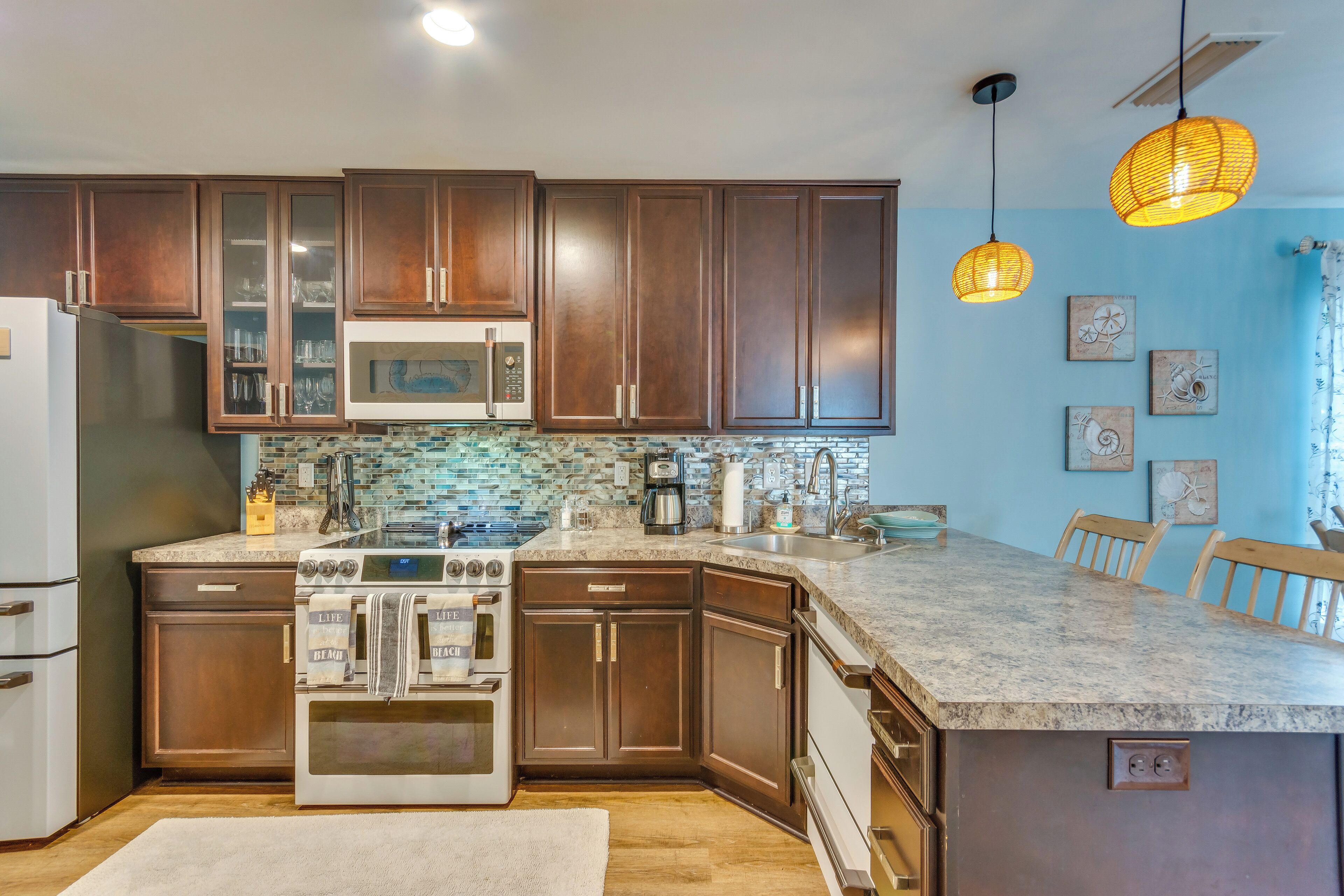 A kitchen with dark wooden cabinets, a stainless steel refrigerator, a built-in oven, a microwave, a coffee maker, and a granite countertop.