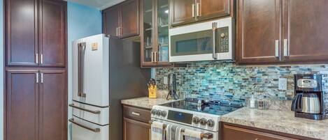 Una cocina con armarios de madera oscura, un refrigerador de acero inoxidable, un microondas, una estufa y una cafetera.