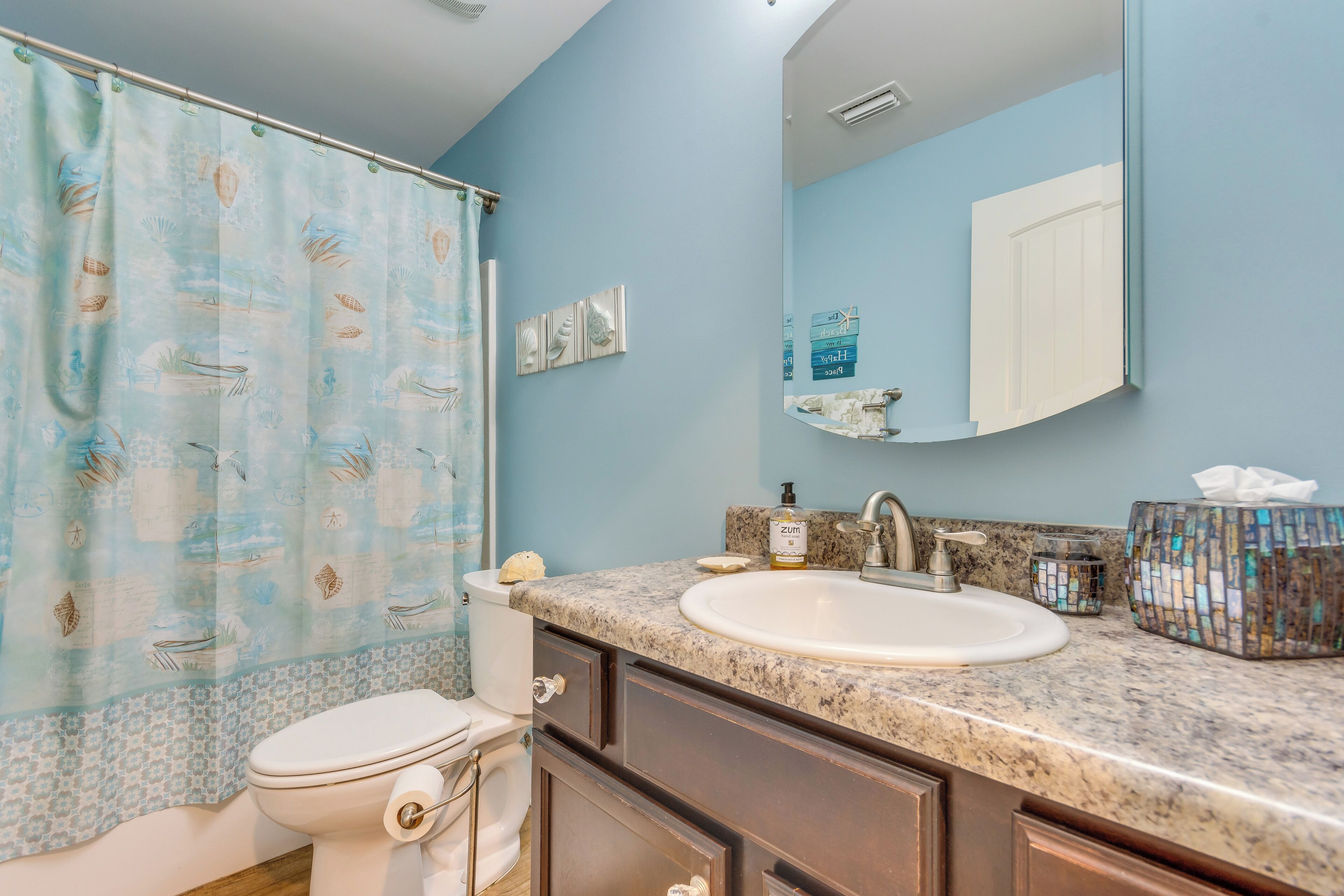 A bathroom with a toilet, sink, and shower curtain.
