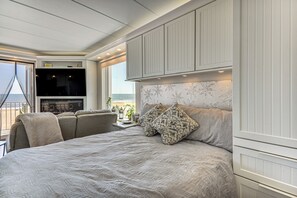 Quarto com cama grande, televisão e vista para o mar.