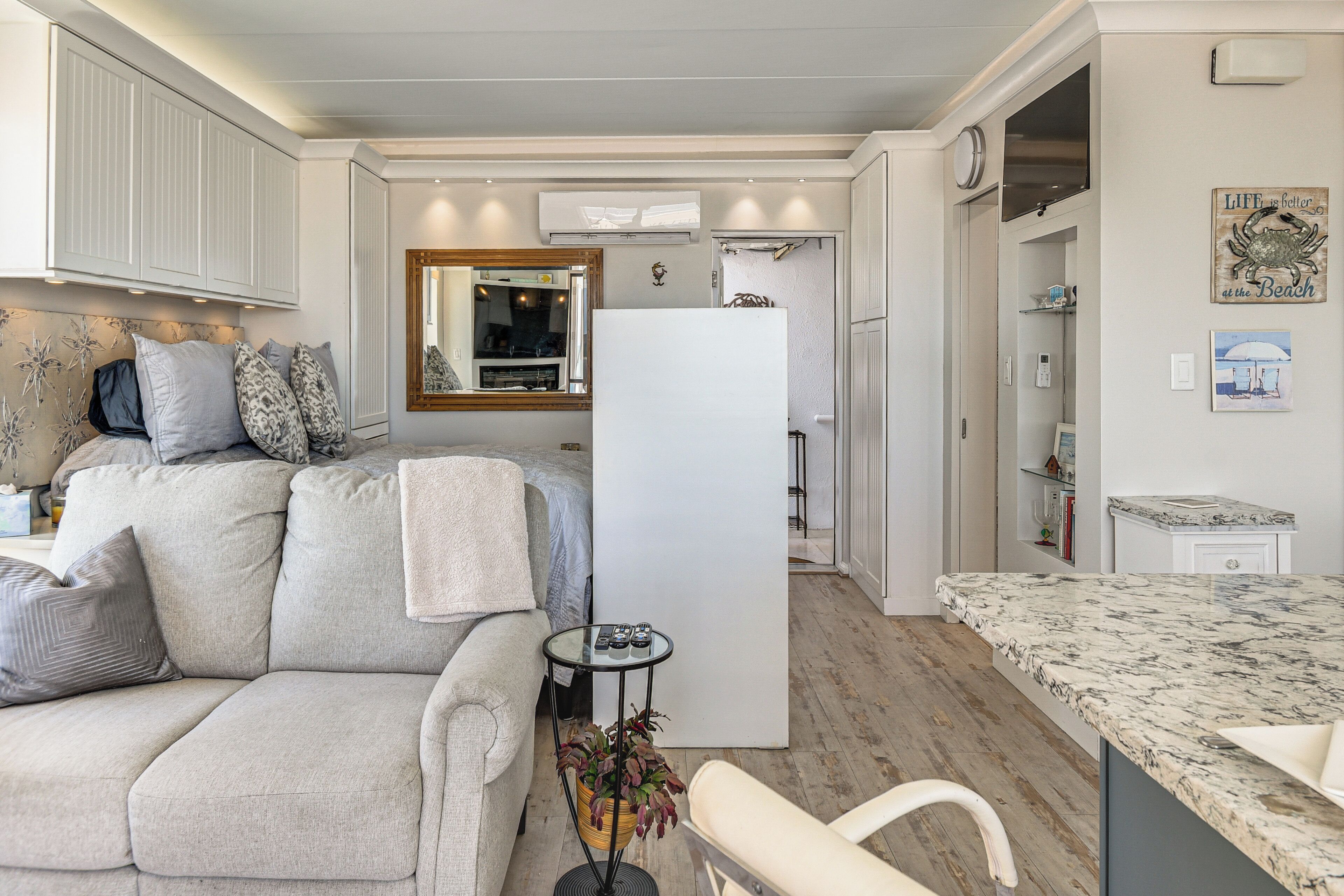 A compact living space with a sofa, a small side table, a refrigerator, and a kitchen area.