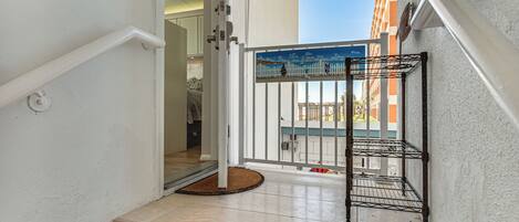A staircase leading to a balcony with a metal rack, a white door, and a view of a building.