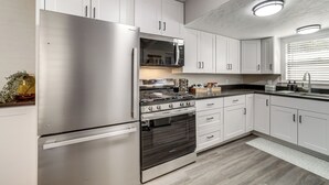 Een moderne keuken met roestvrijstalen apparatuur, witte kasten en een marmeren spatwand.