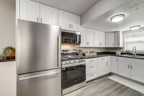 A modern kitchen with stainless steel appliances, white cabinetry, and a marble backsplash. - Historic Prescott Gem! Walk to Whiskey Row! (Prescott)