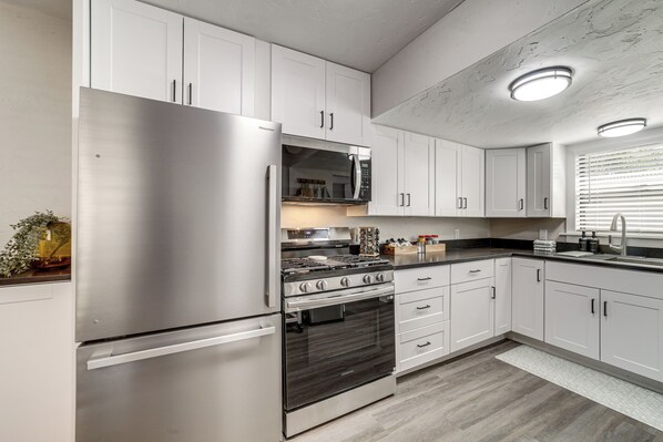 Una cocina moderna con electrodomésticos de acero inoxidable, armarios blancos y una salpicadera de mármol.