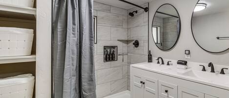 A bathroom with a bathtub, a large mirror, and a vanity with a sink.