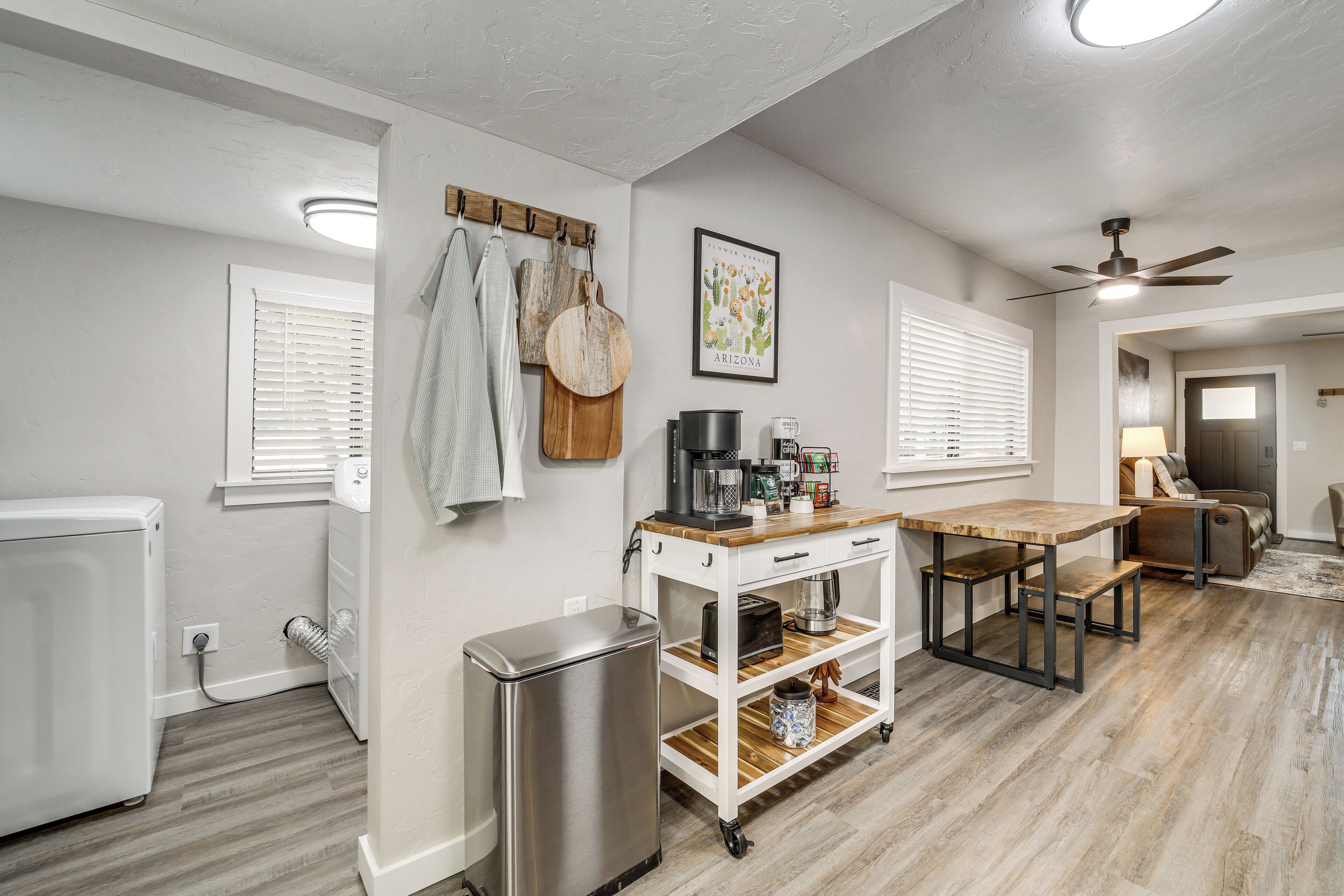 A kitchen with a refrigerator, a coffee maker, and a wooden table.