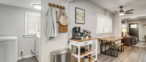 A kitchen with a refrigerator, a coffee maker, and a wooden table.