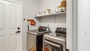 A laundry room with two washing machines, a dryer, a shelf with toiletries, and a first aid kit. - Saguaro Sanctuary: Tucson Home w/ Outdoor Oasis (Tucson)