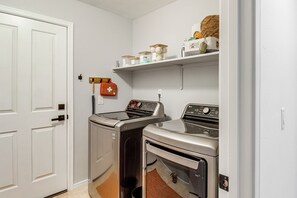 A laundry room with two washing machines, a dryer, a shelf with toiletries, and a first aid kit. - Saguaro Sanctuary: Tucson Home w/ Outdoor Oasis (Tucson)