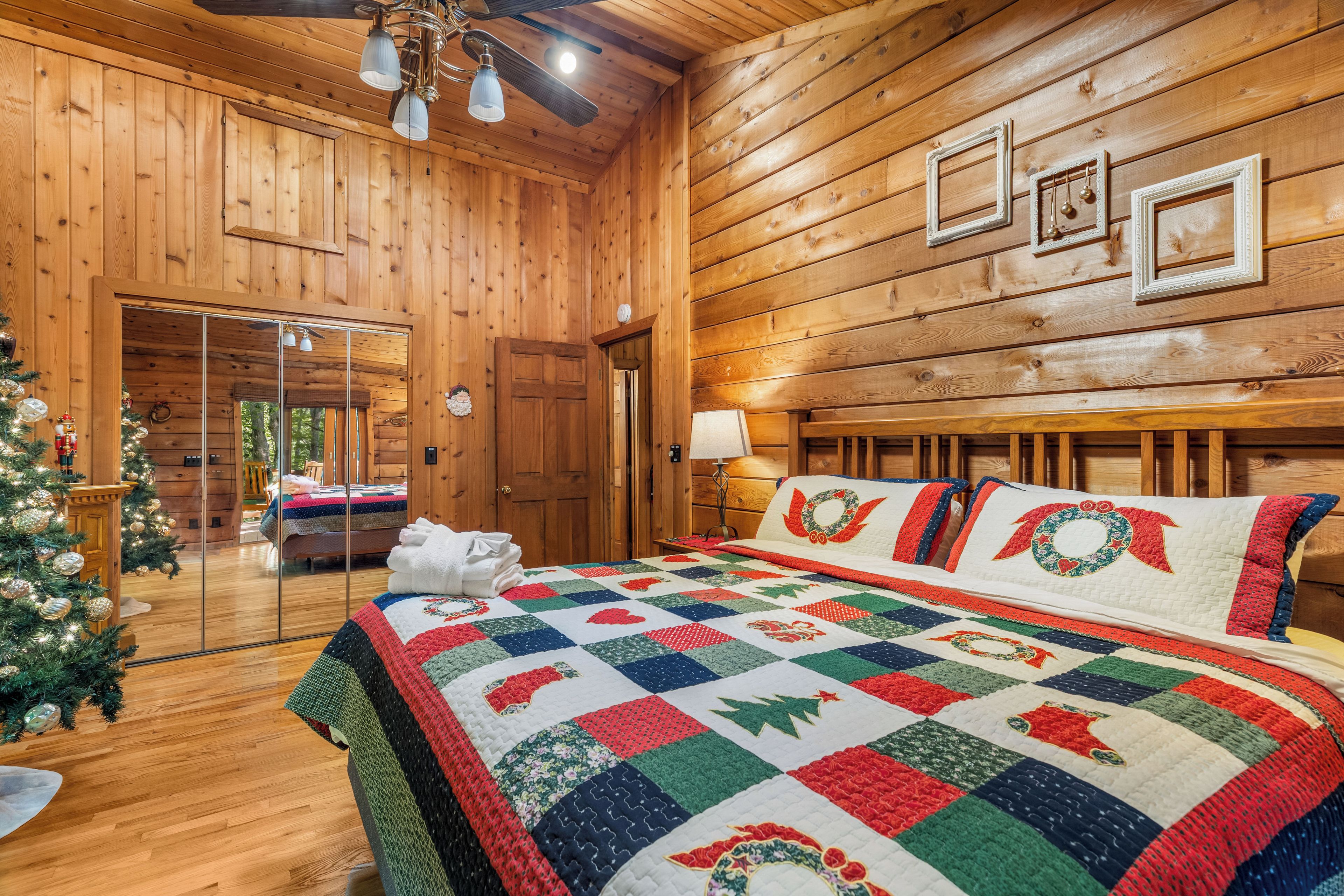 A cozy log cabin bedroom with a large bed, a Christmas tree, and a view of the outside.