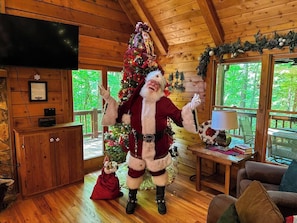 Ein Holzblockhaus-Interieur mit einem geschmückten Weihnachtsbaum, einem Fernseher und einer gemütlichen Sitzecke.
