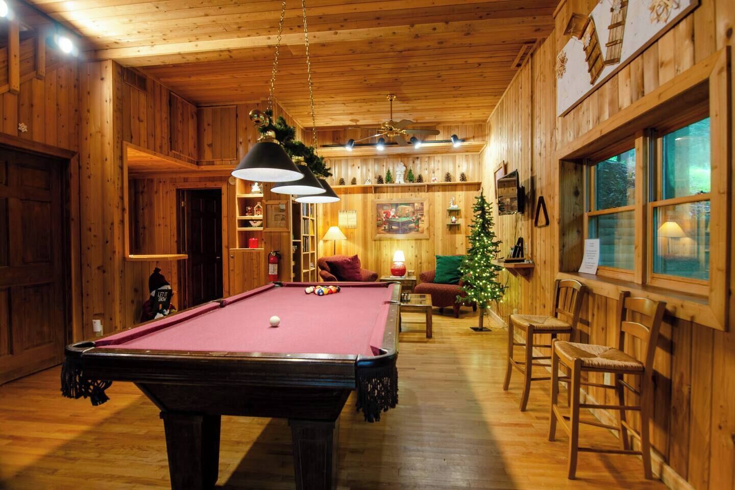 Ein Holzinterieur mit Billardtisch, Sitzgruppe und einem Weihnachtsbaum.