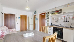 Una cucina compatta con tavolo, sedie, fornello e pensili.