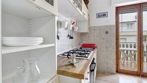Una cucina con piano cottura a gas, lavello e zona pranzo con tavolo e sedie.