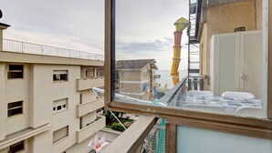 Un edificio a più piani con balconi, vista su una torre gialla da una finestra e un armadio bianco.