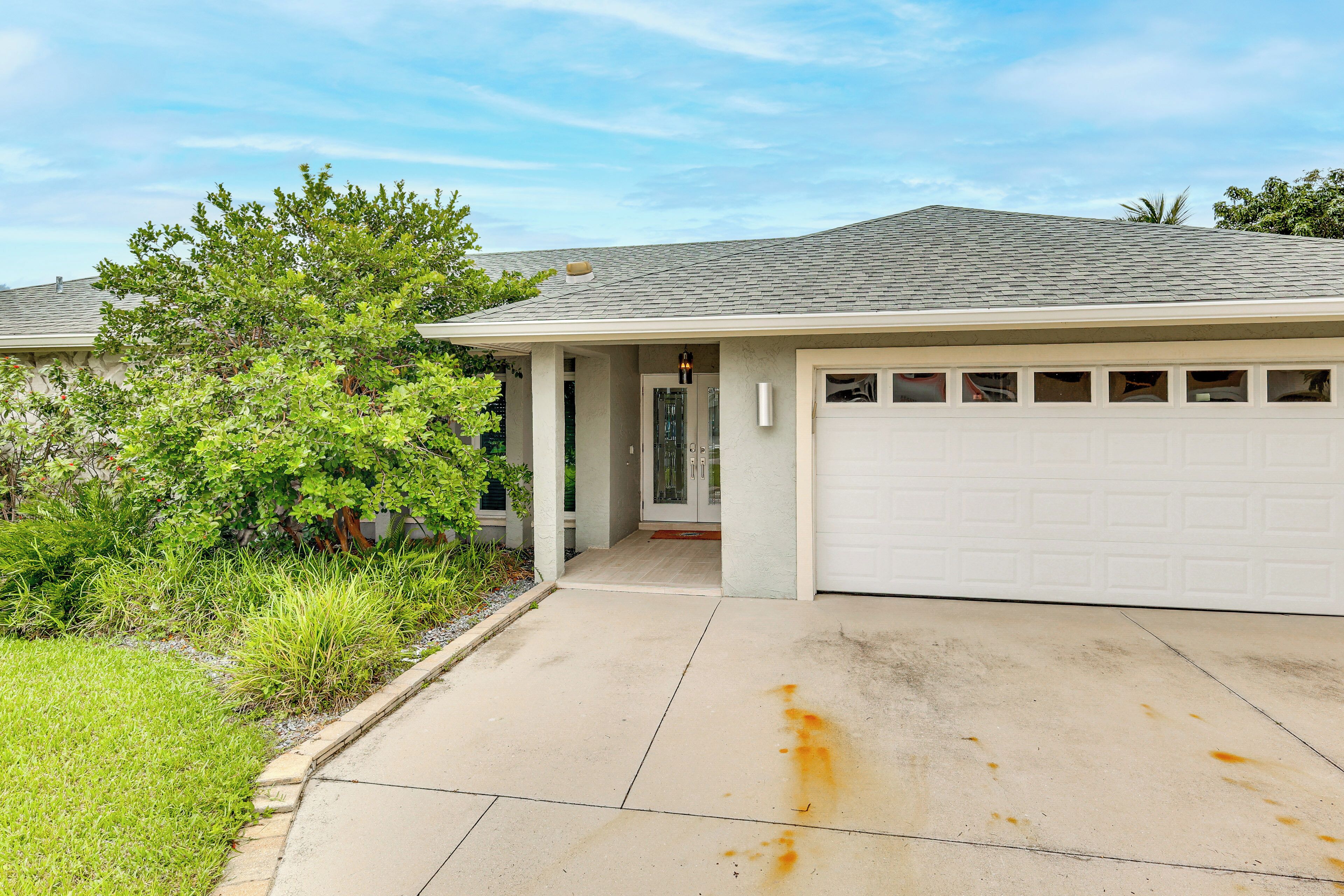A residential house with a garage, a driveway, and a well-maintained lawn.