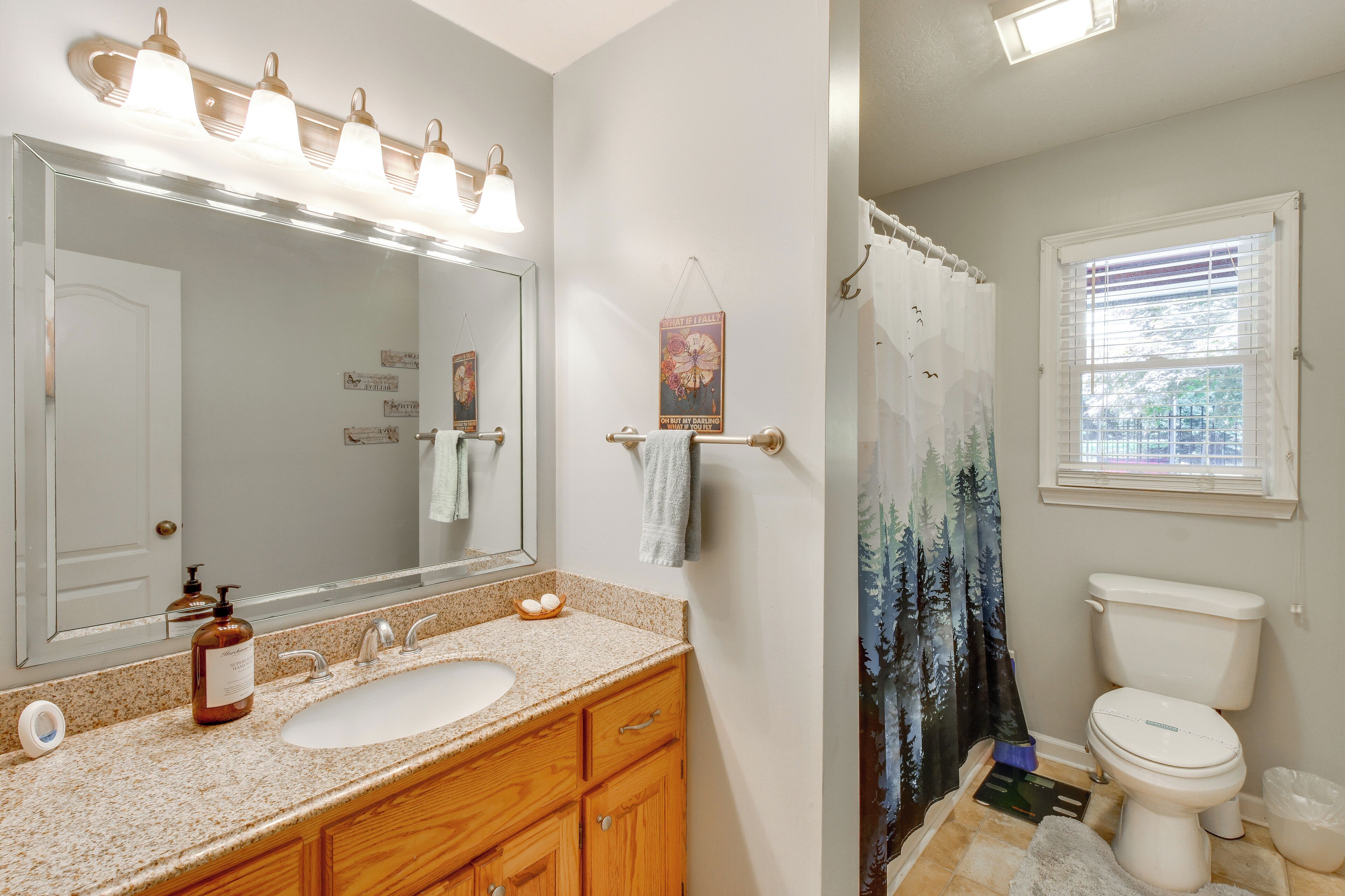 A bathroom with a sink, mirror, vanity, and toilet.
