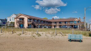 A beachfront hotel with multiple balconies, a sandy beach in front, and a bench. - Steps to Beach! OOB Studio w/ Grill Access (Old Orchard Beach)