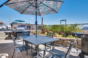 Un patio al aire libre con una mesa, sillas, una parrilla y un parasol decorativo.