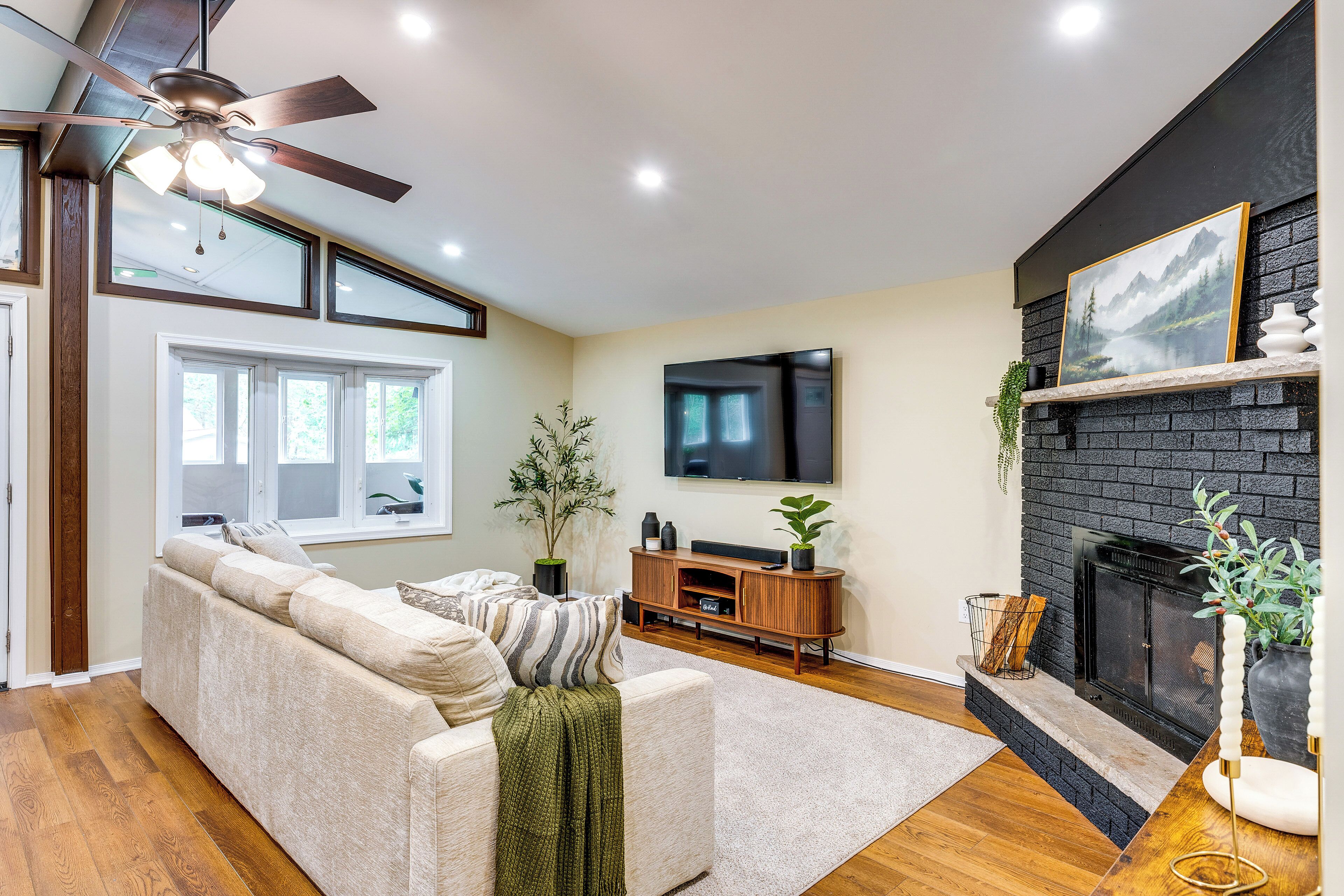 A living room with a sofa, TV, fireplace, and ceiling fan.