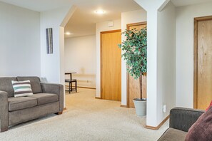 A living room with a sofa, a potted plant, and a wooden door. - 6 Mi to Kenai Beach! Cozy Ocean-view Escape (Kenai)