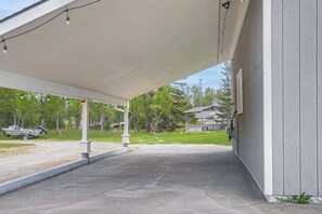 A covered outdoor area with a concrete floor, a boat on the left, and a building with a white exterior on the right. - 6 Mi to Kenai Beach! Cozy Ocean-view Escape (Kenai)