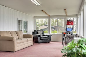 A room with a beige sofa, a black leather chair, a basketball hoop, and a large window. - 6 Mi to Kenai Beach! Cozy Ocean-view Escape (Kenai)
