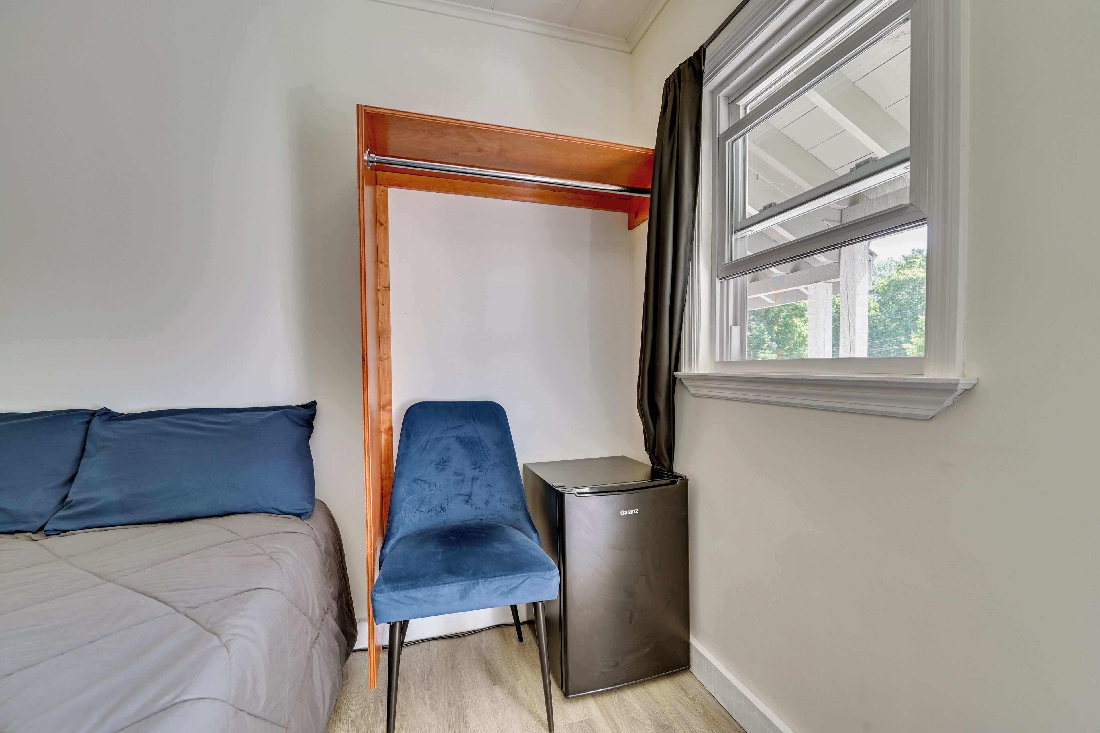Een slaapkamer met een bed, een stoel, een klein tafeltje, een raam en een deur.