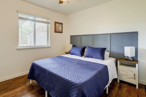 Un dormitorio con cama, mesita de noche y una imagen colgada en la pared.