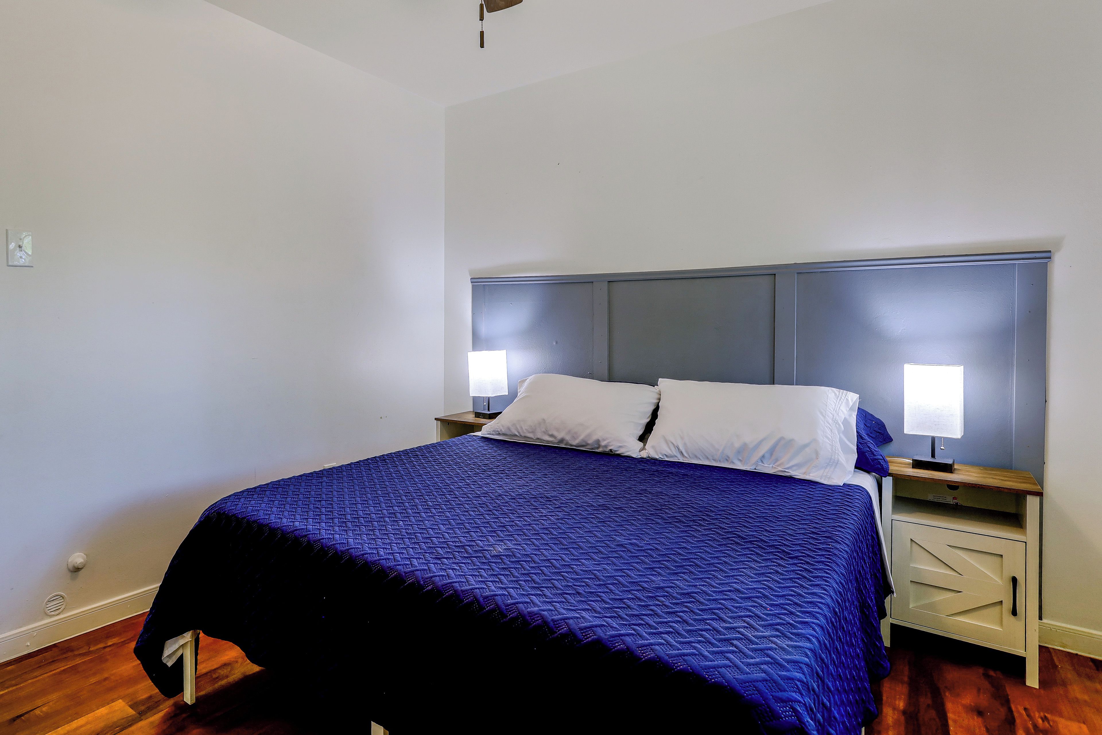 A single bed with a headboard, two bedside tables, and a nightstand with a lamp.