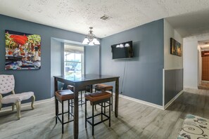A dining area with a bar table, two bar stools, a single chair, and a television mounted on the wall. - Suburban Sanctuary: Magnolia Home w/ Backyard! (Magnolia)