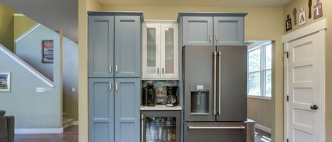 Eine Küche mit grauen Schränken, einem Edelstahl-Kühlschrank und einer Kaffeemaschine auf der Arbeitsplatte.