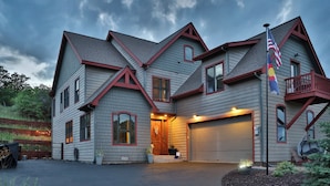 A two-story house with a garage, a balcony, and a flagpole.