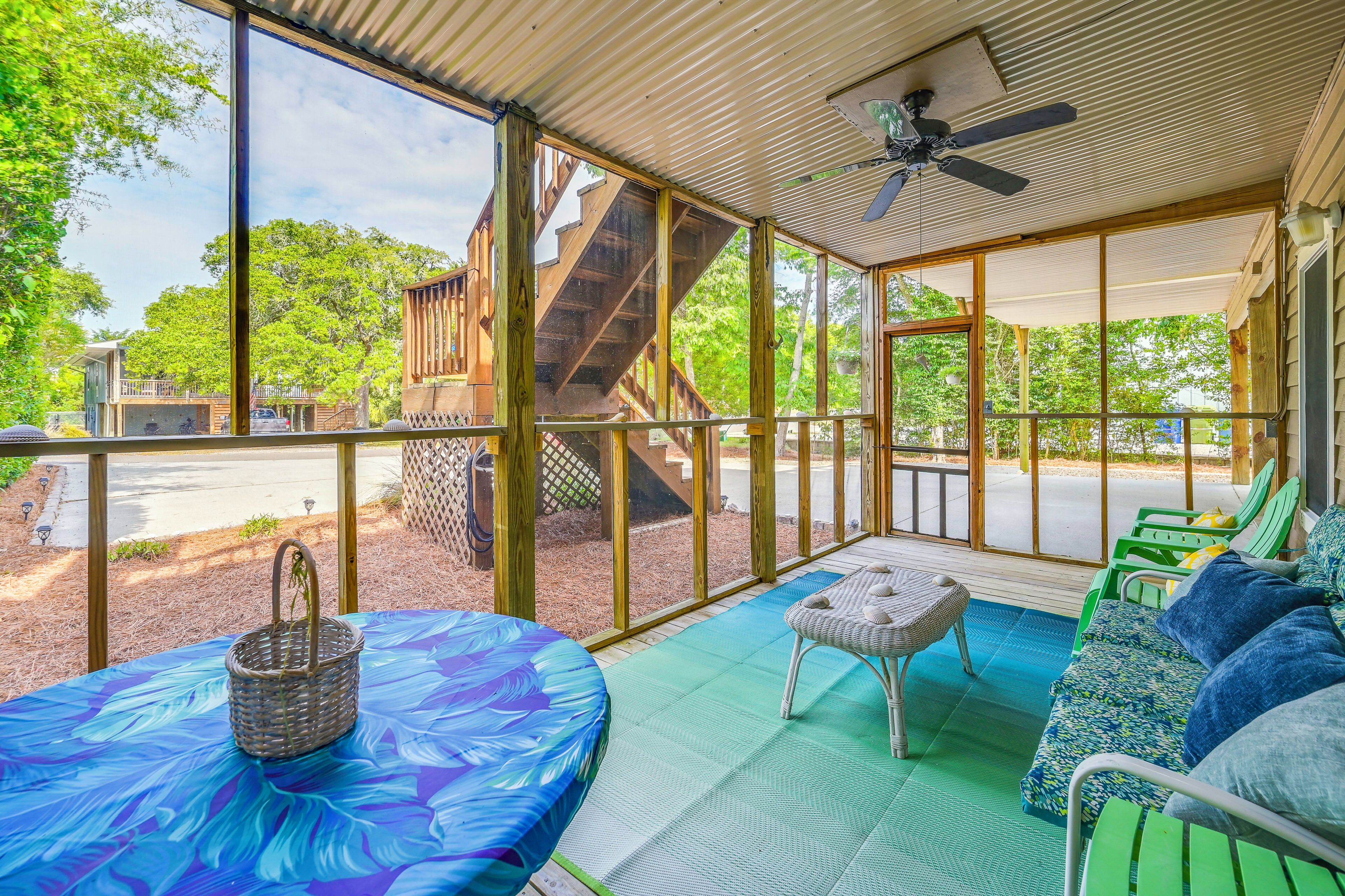 A covered outdoor seating area with a table, chairs, and a ceiling fan.