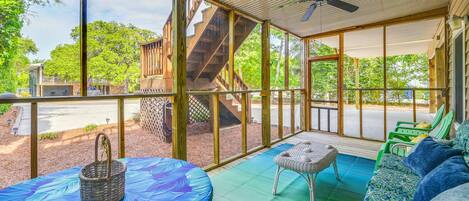 A covered outdoor seating area with a table, chairs, and a ceiling fan.
