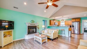 A living room with a fireplace, a sofa, a coffee table, and a television. - Steps to Beach! Emerald Isle Group Escape w/ Yard (Emerald Isle)