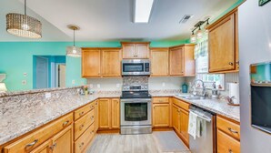 A kitchen with wooden cabinets, a stainless steel oven, a microwave, and granite countertops. - Steps to Beach! Emerald Isle Group Escape w/ Yard (Emerald Isle)