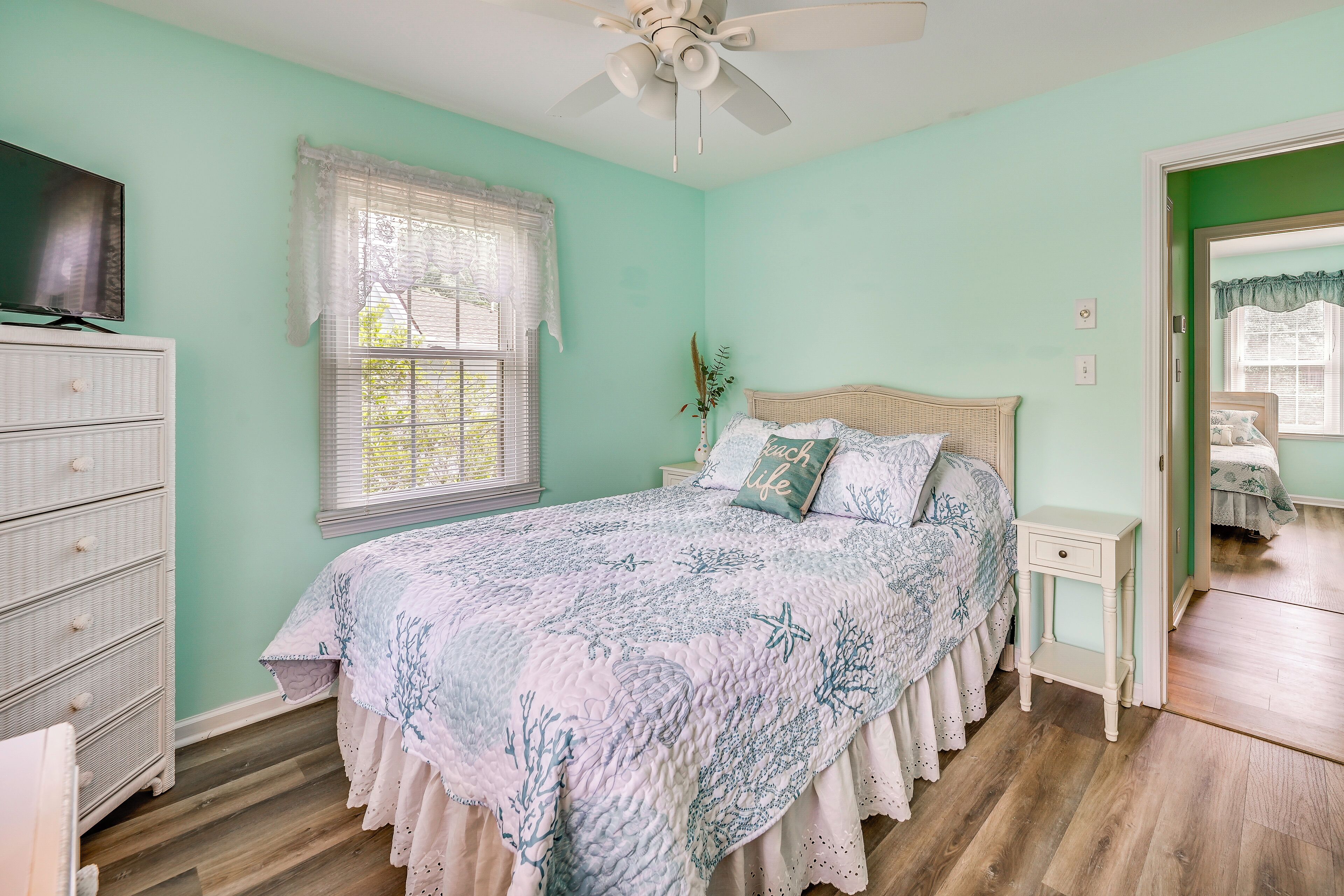 A bedroom with a bed, dresser, nightstand, and a ceiling fan.
